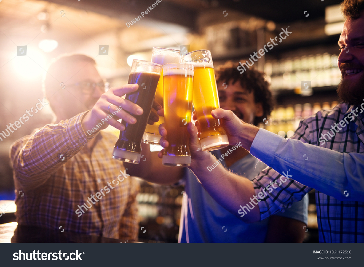 stock-photo-focus-view-of-hands-and-beer-glasses-while-happy-casual-multicultural-friends-clinking-beer-glasses-1061172590